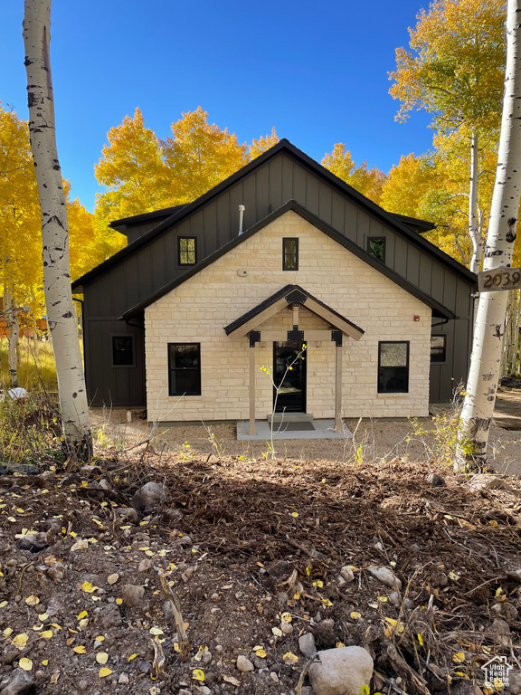 Bungalow featuring board and batten siding and stone siding