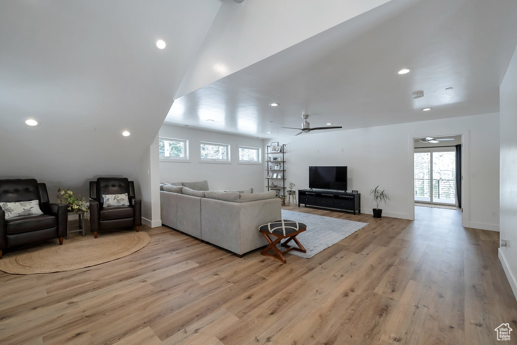 Living area featuring a healthy amount of sunlight, ceiling fan, light wood finished floors, and vaulted ceiling