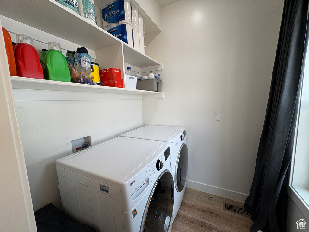 Washroom featuring laundry area, visible vents, wood finished floors, washer and dryer, and baseboards