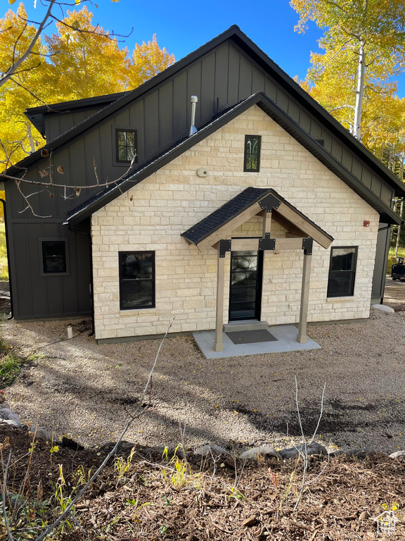 Back of house featuring board and batten siding and stone siding