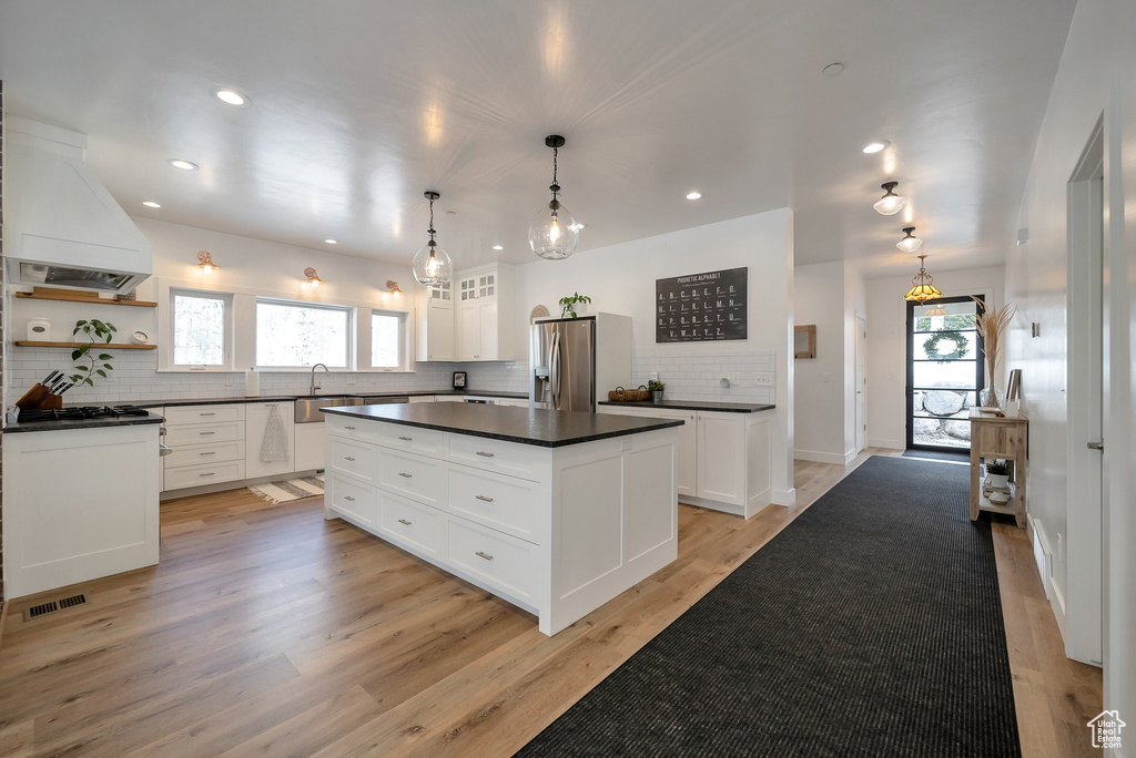 Kitchen with tasteful backsplash, dark countertops, stainless steel fridge, and a healthy amount of sunlight
