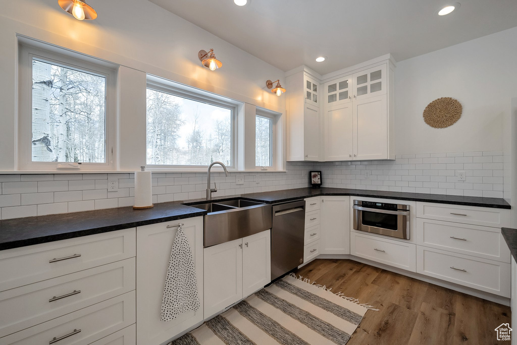 Kitchen with white cabinetry, a sink, appliances with stainless steel finishes, dark countertops, and recessed lighting