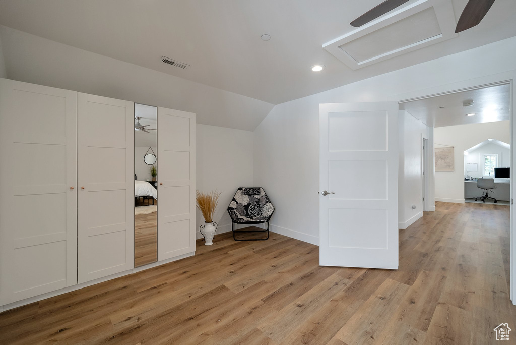 Bonus room with attic access, light wood-style floors, visible vents, vaulted ceiling, and baseboards