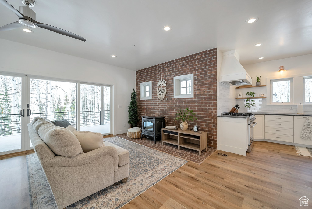 Living room with ceiling fan, recessed lighting, light wood-style flooring, and a wood stove