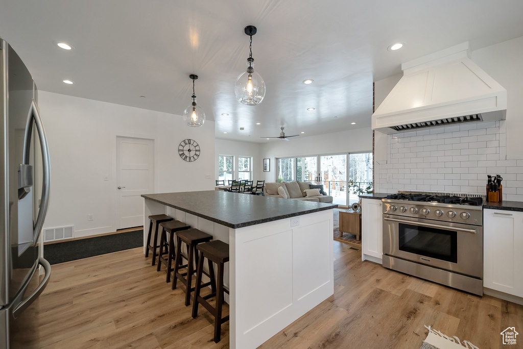 Kitchen featuring visible vents, stainless steel appliances, dark countertops, and a kitchen breakfast bar