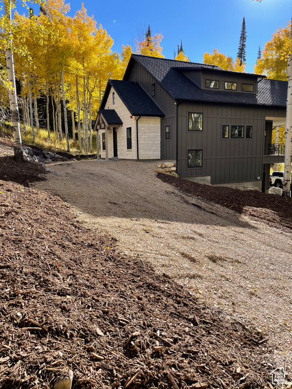 Exterior space featuring board and batten siding, an attached garage, driveway, and roof with shingles
