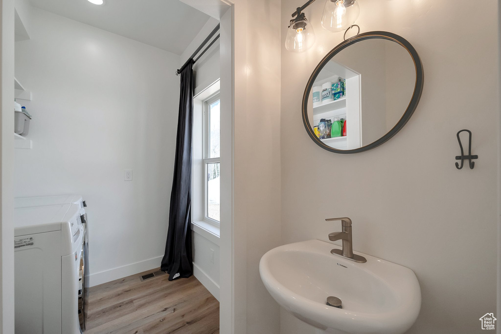 Bathroom with wood finished floors, independent washer and dryer, a sink, baseboards, and visible vents