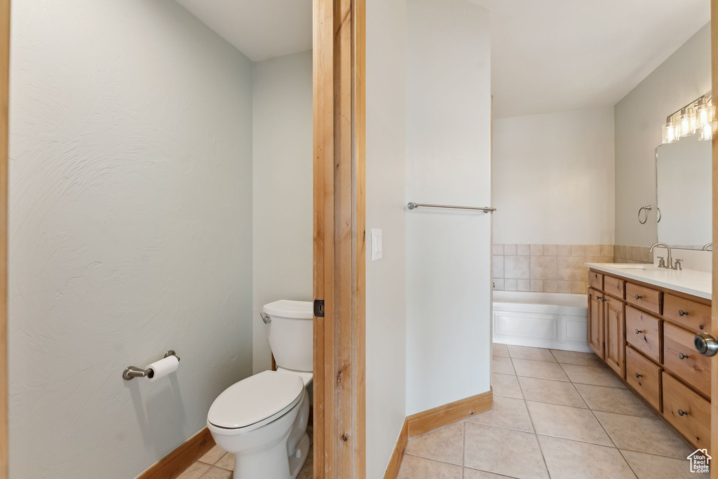 Bathroom with vanity, tile patterned floors, toilet, baseboards, and a garden tub