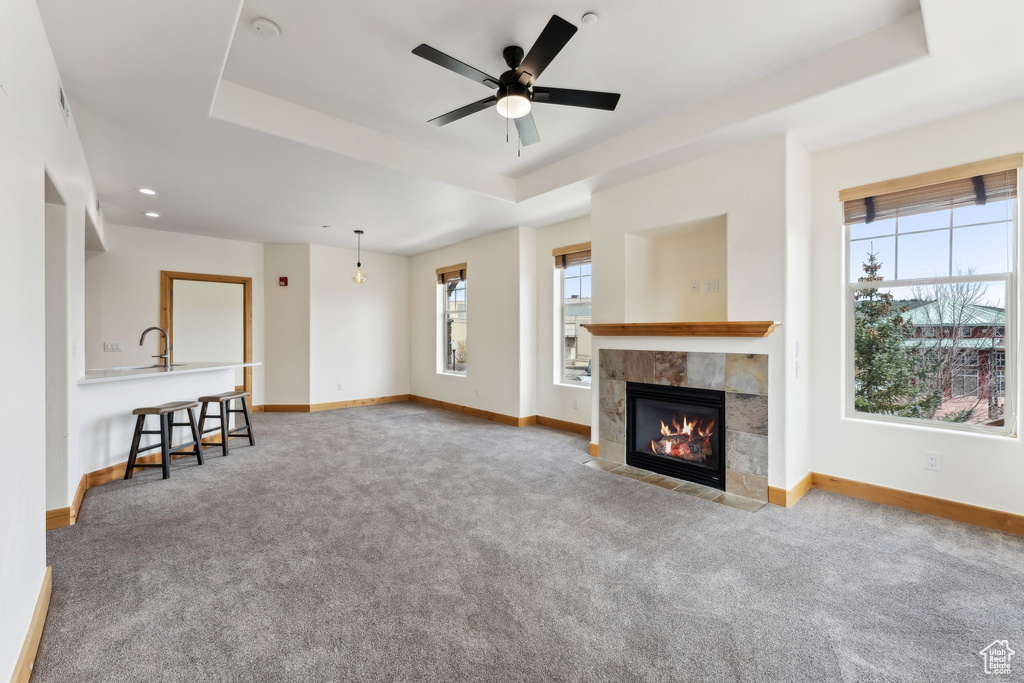 Unfurnished living room with baseboards, a raised ceiling, a ceiling fan, and carpet floors