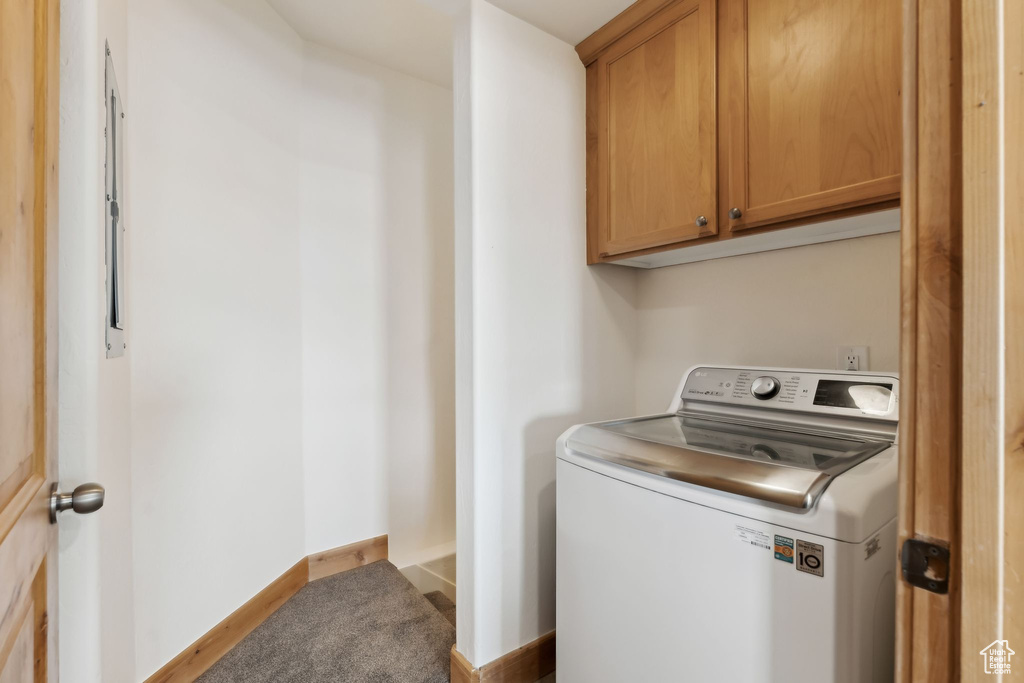 Washroom with cabinet space, washer / dryer, and baseboards