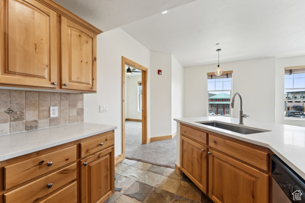 Kitchen featuring stainless steel dishwasher, a sink, tasteful backsplash, and light countertops