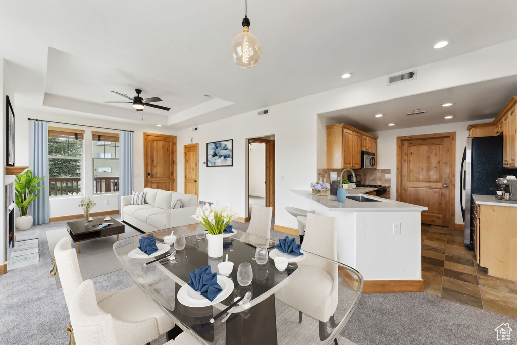 Carpeted dining room with a sink, a ceiling fan, recessed lighting, and visible vents
