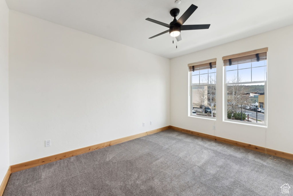 Empty room featuring a ceiling fan, carpet, and baseboards
