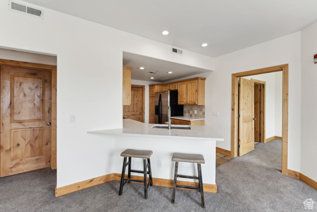 Kitchen featuring light colored carpet, light countertops, baseboards, visible vents, and refrigerator with ice dispenser