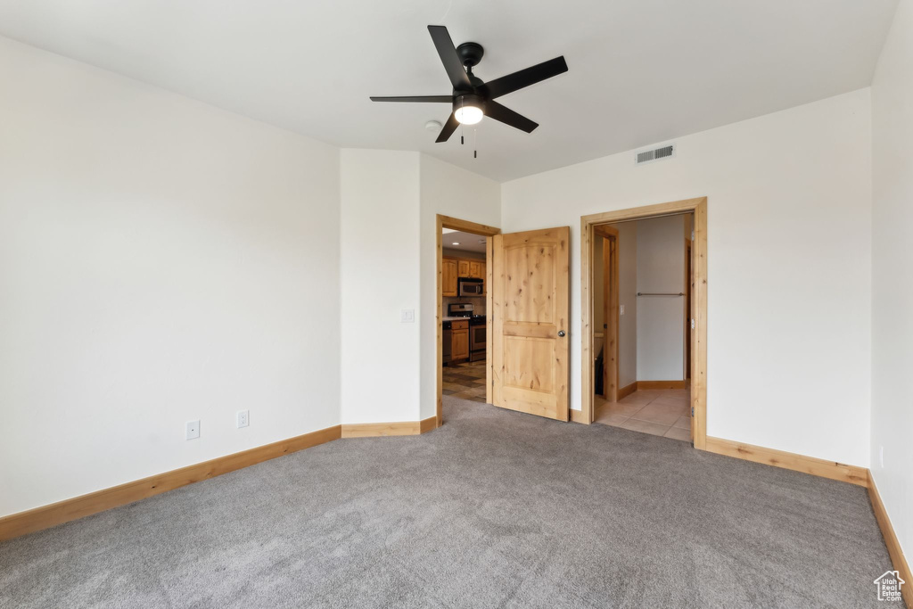 Unfurnished bedroom featuring baseboards, visible vents, a ceiling fan, and carpet flooring