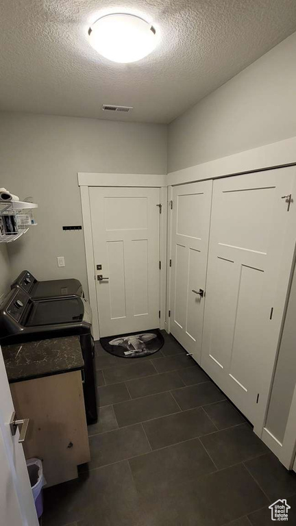Laundry room featuring laundry area, separate washer and dryer, a textured ceiling, dark tile patterned floors, and visible vents