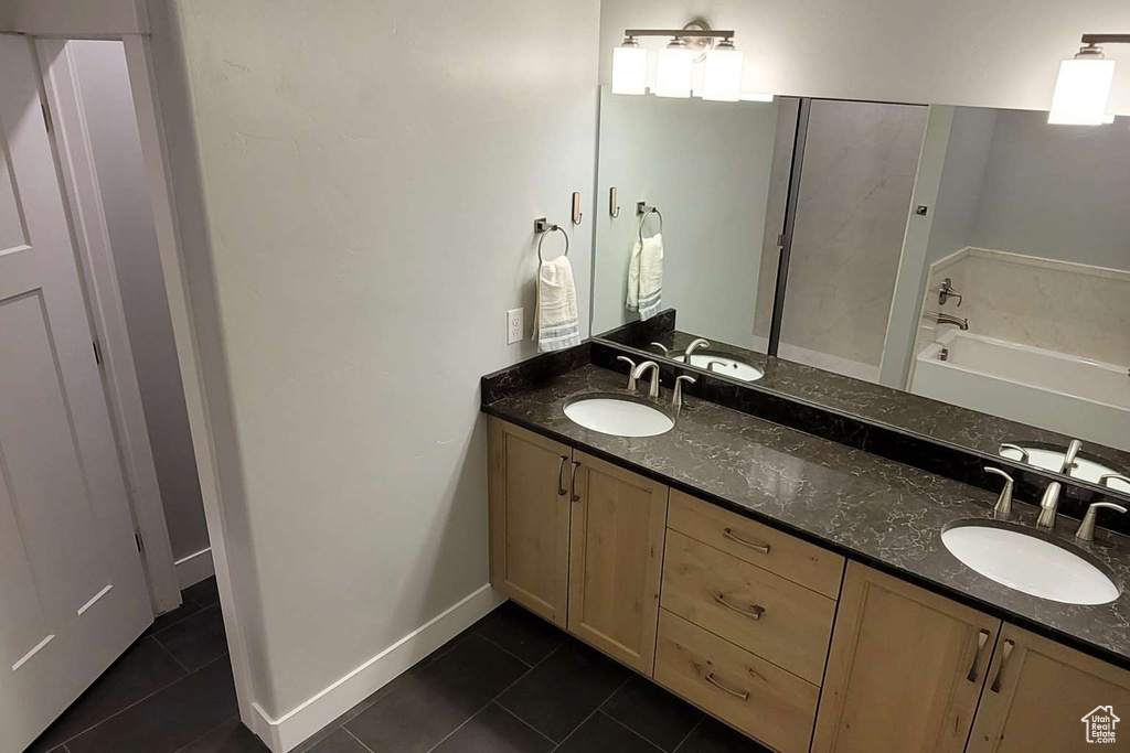 Full bath with double vanity, a sink, tile patterned flooring, and a garden tub