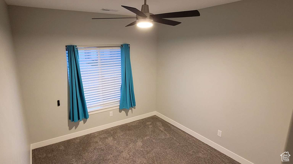 Spare room with baseboards, ceiling fan, and dark colored carpet