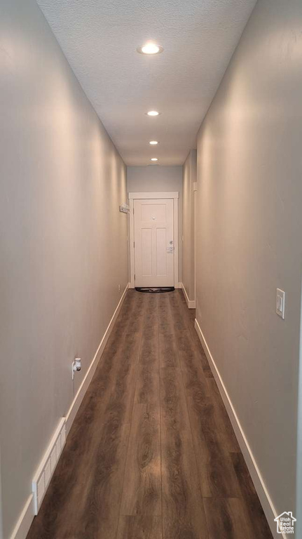 Hallway featuring visible vents, baseboards, dark wood-style floors, recessed lighting, and a textured ceiling