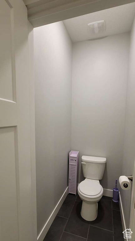 Bathroom with tile patterned floors, baseboards, and toilet
