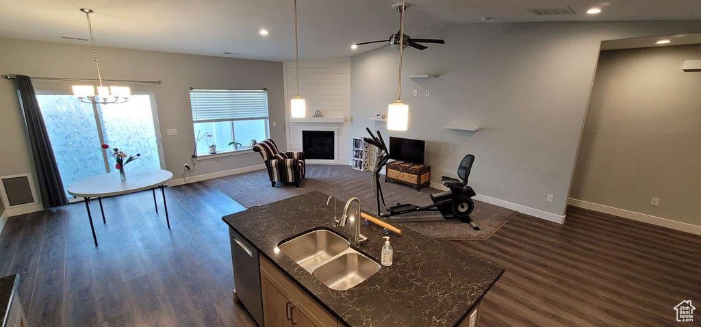 Kitchen with a sink, baseboards, ceiling fan with notable chandelier, lofted ceiling, and open floor plan