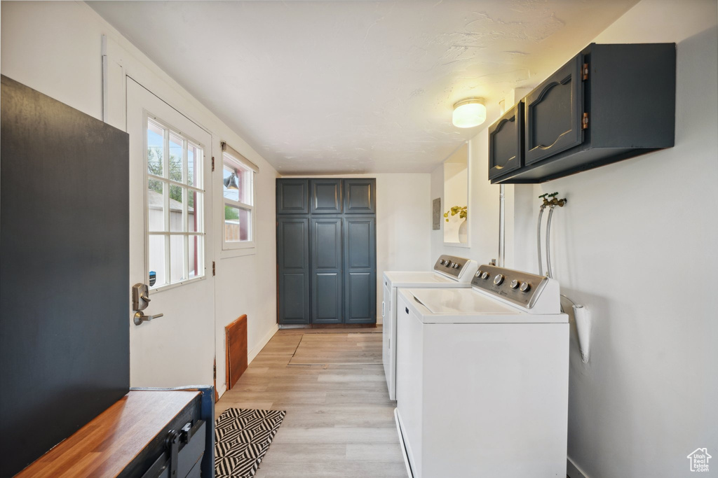 Clothes washing area featuring light wood finished floors, cabinet space, independent washer and dryer, and baseboards