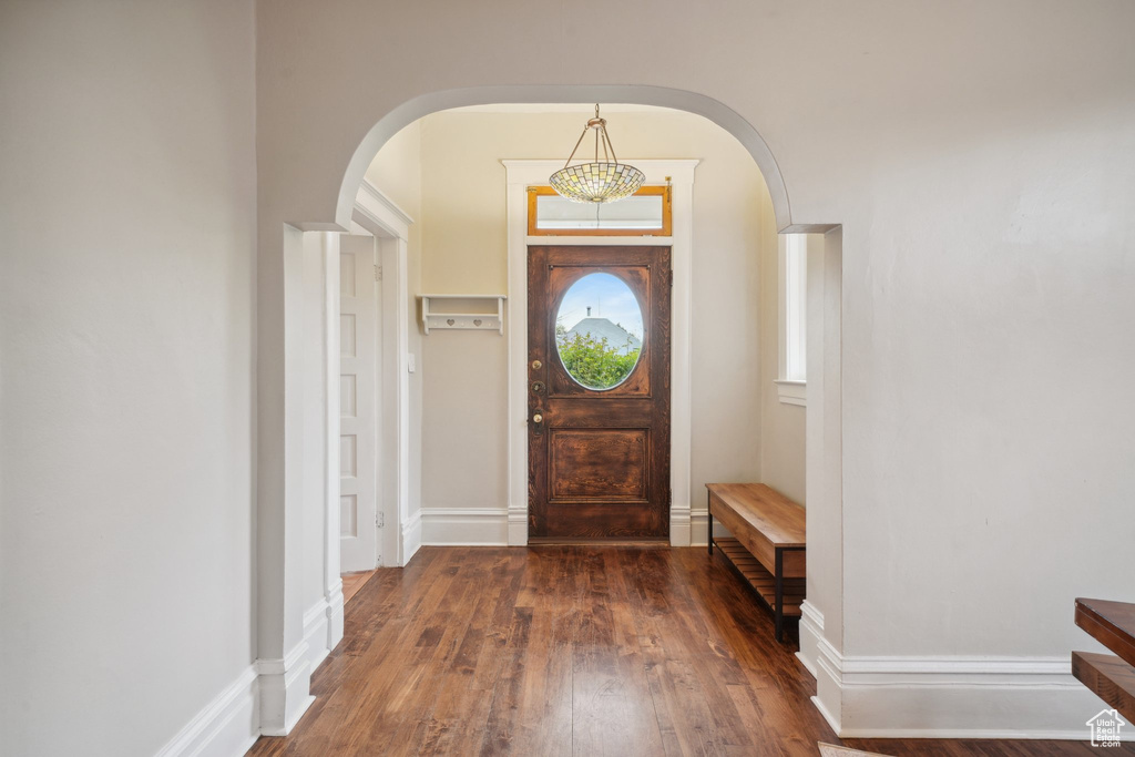 Entrance foyer with baseboards, arched walkways, and wood finished floors