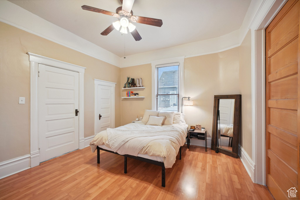 Bedroom with baseboards, light wood-type flooring, and a ceiling fan