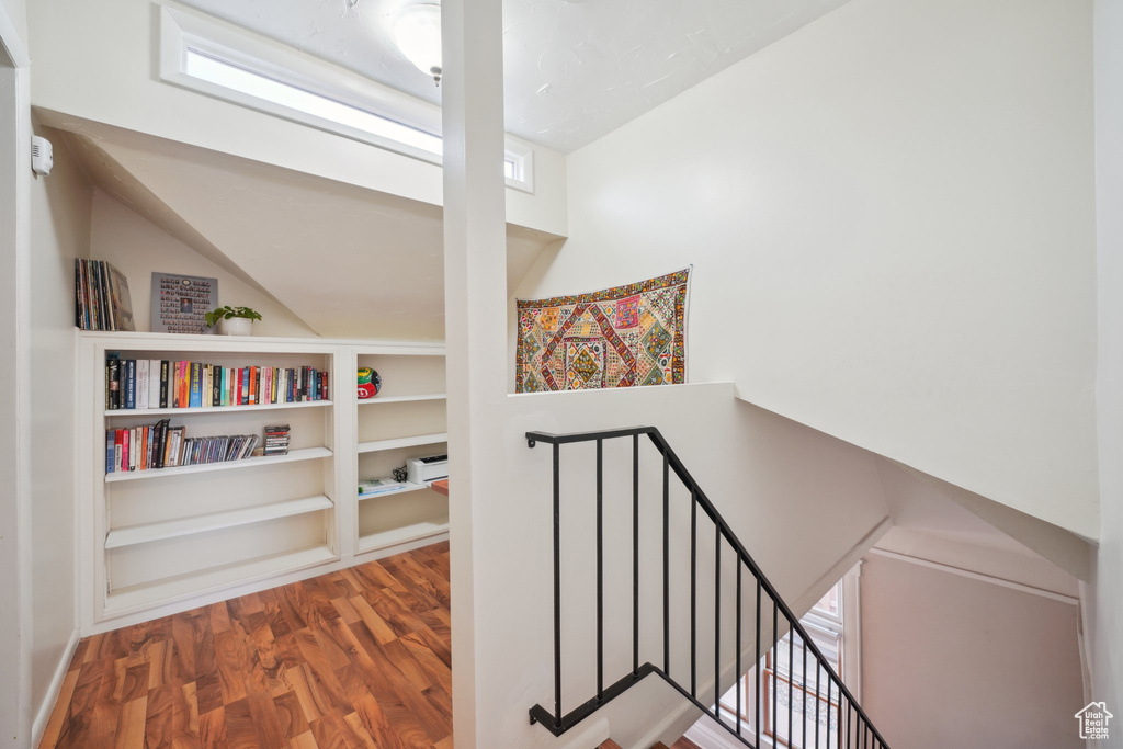 Corridor featuring wood finished floors, an upstairs landing, lofted ceiling, and built in features