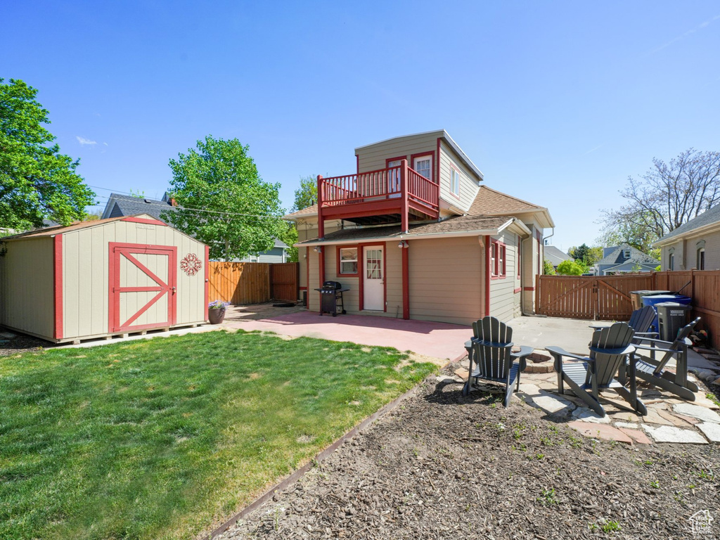 Rear view of house with a patio area, an outbuilding, a fenced backyard, a lawn, and a storage unit