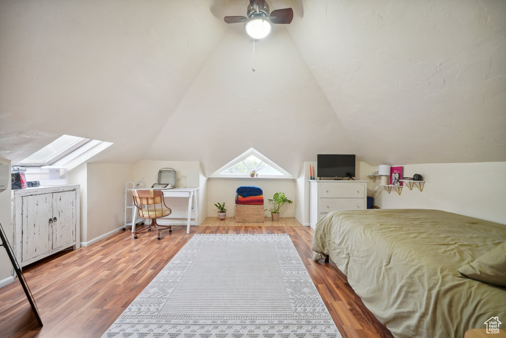 Bedroom featuring wood finished floors, ceiling fan, and vaulted ceiling with skylight