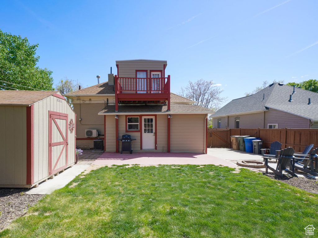 Back of house with an outdoor structure, a storage unit, a patio area, fence, and a yard
