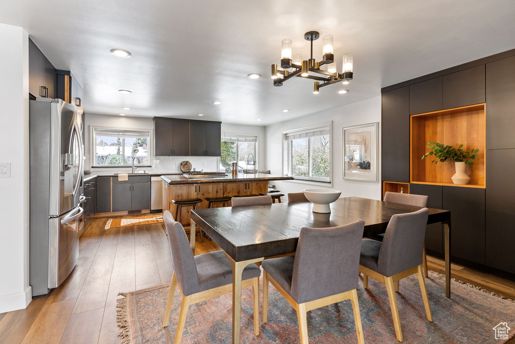 Dining space with recessed lighting, light wood-style flooring, and a notable chandelier