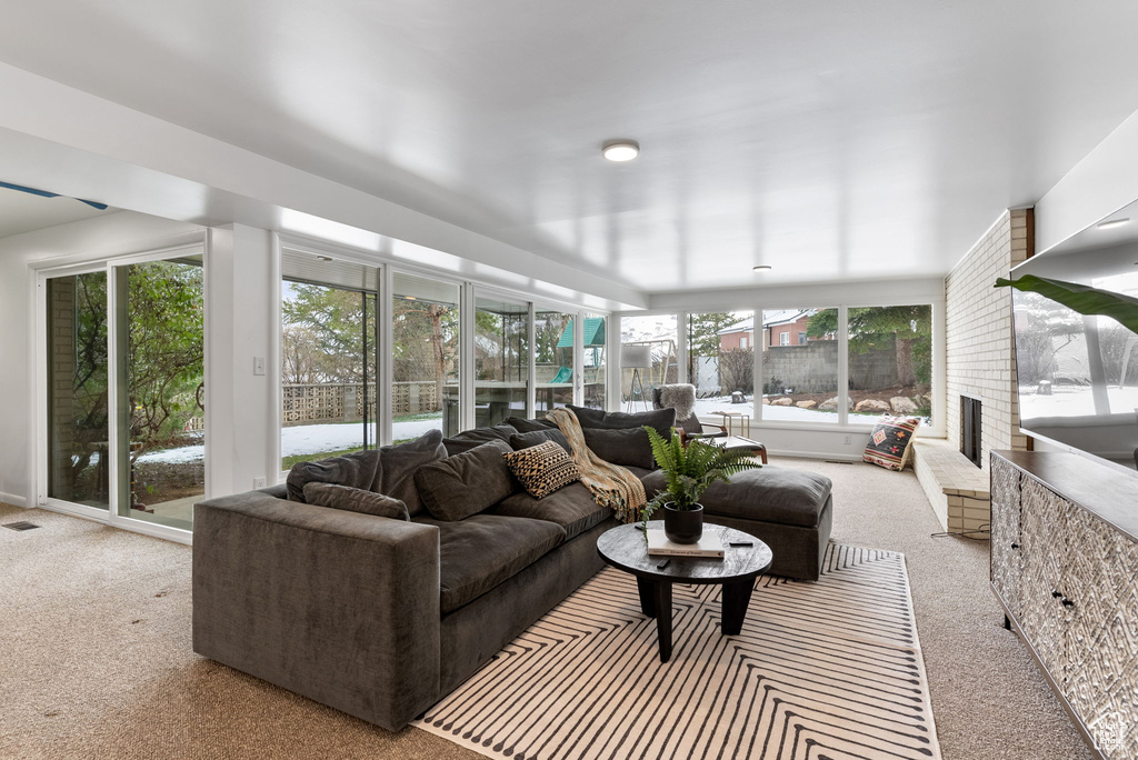 Sunroom with carpet, an outdoor living space with a fireplace, and visible vents