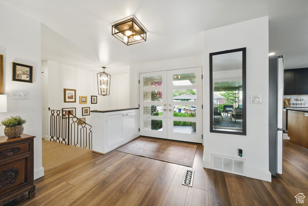 Foyer entrance featuring visible vents, wood finished floors, french doors, and an inviting chandelier