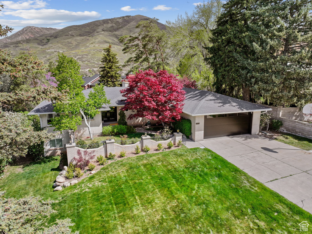 View of front of house with a mountain view, concrete driveway, brick siding, and a front yard