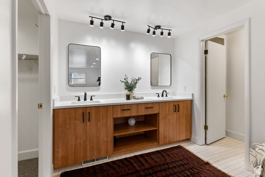 Bathroom with a sink, baseboards, double vanity, and visible vents