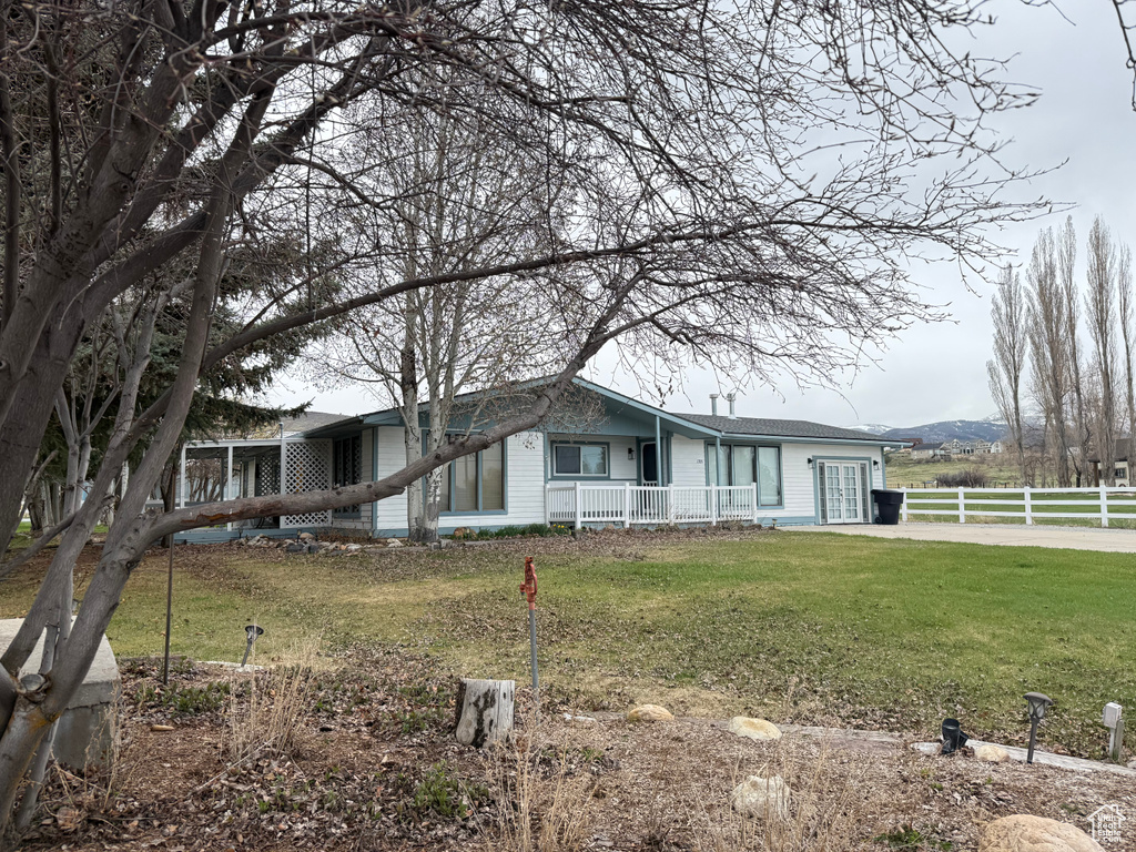View of front facade with a porch, fence, and a front yard