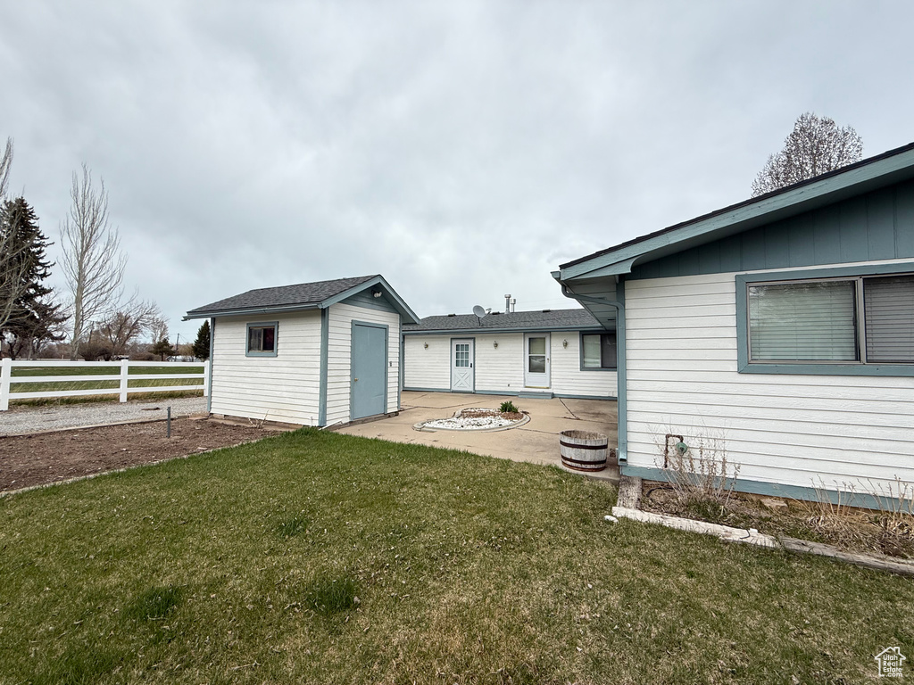 Back of property with fence, an outdoor structure, a shed, a lawn, and a patio