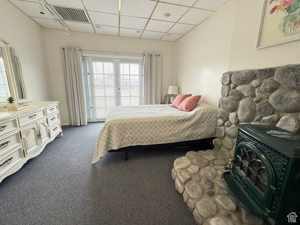Bedroom with dark carpet, access to outside, a drop ceiling, and visible vents