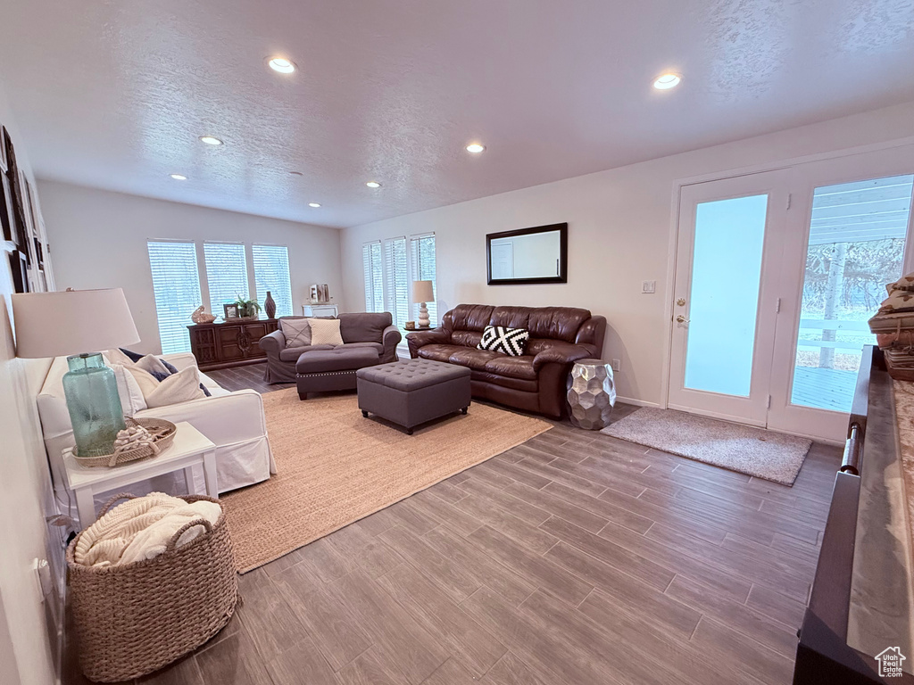 Living room featuring baseboards, a textured ceiling, recessed lighting, and wood finished floors