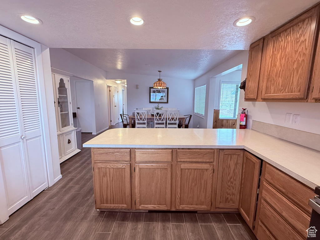 Kitchen featuring light countertops, a peninsula, a textured ceiling, and dark wood-type flooring