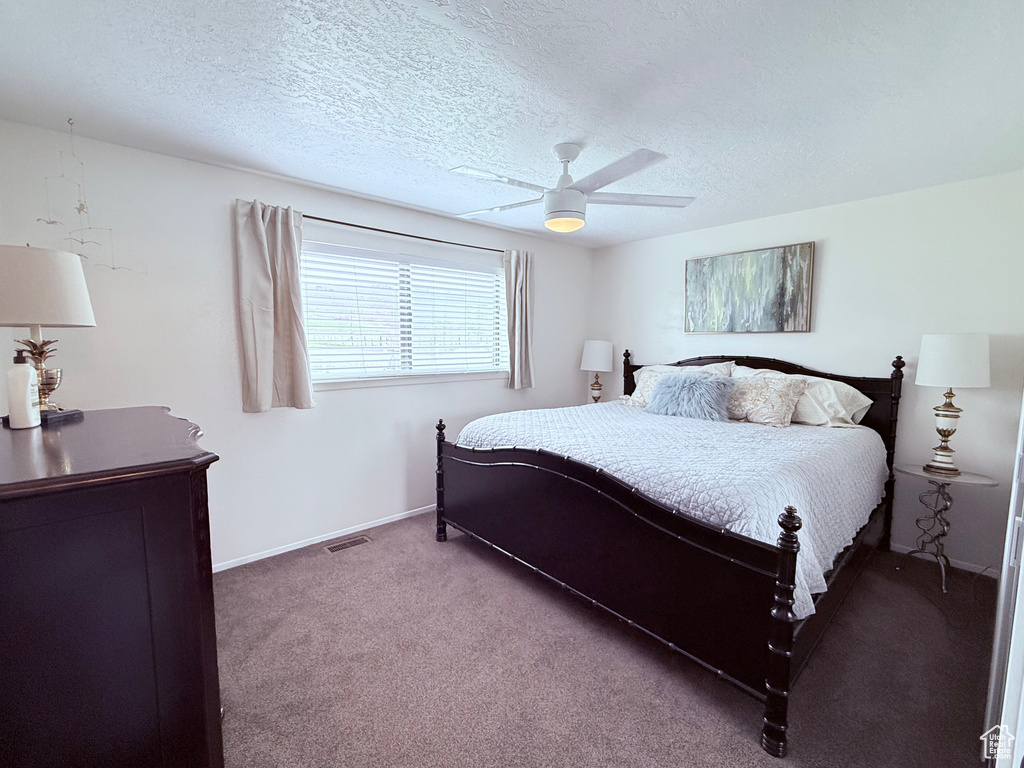 Carpeted bedroom with baseboards, ceiling fan, a textured ceiling, and visible vents