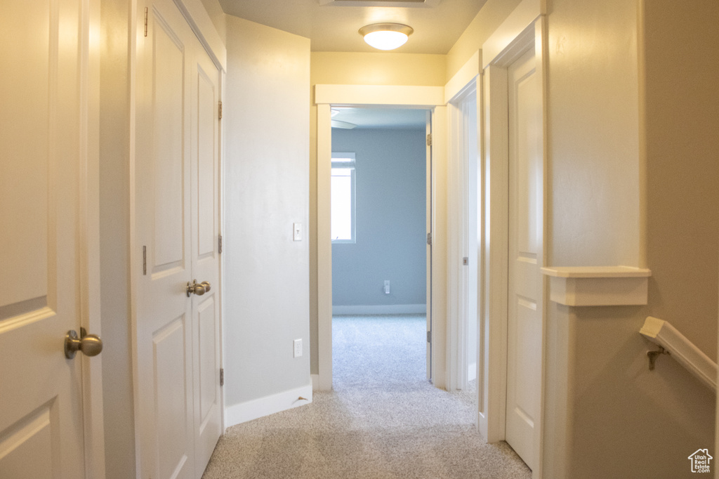 Hall with light colored carpet and baseboards