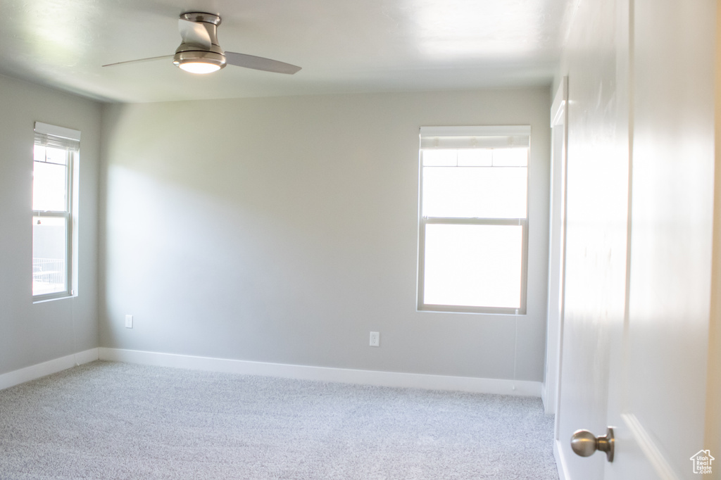 Carpeted empty room with a ceiling fan and baseboards