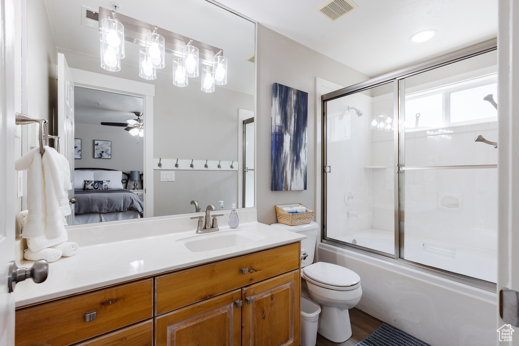 Ensuite bathroom featuring visible vents, vanity, toilet, bath / shower combo with glass door, and connected bathroom