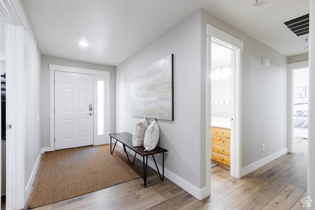 Foyer entrance with baseboards, light wood-type flooring, and visible vents