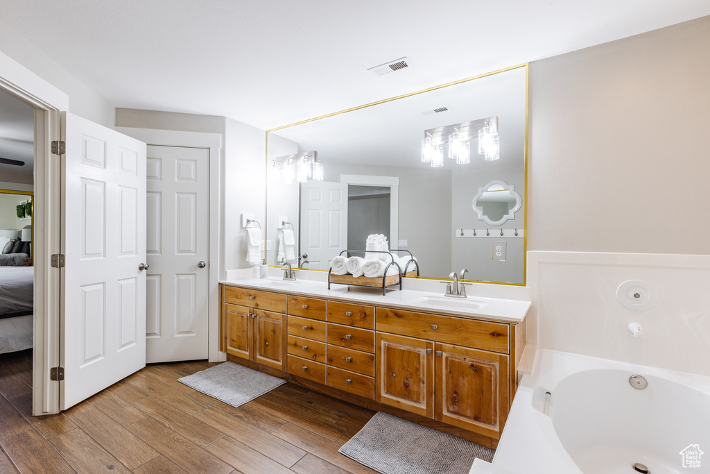 Full bathroom featuring visible vents, double vanity, wood finished floors, connected bathroom, and a sink