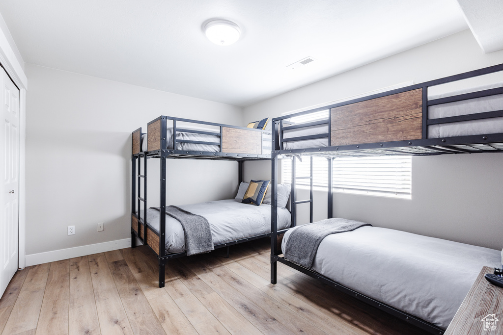 Bedroom with baseboards, a closet, hardwood / wood-style flooring, and visible vents