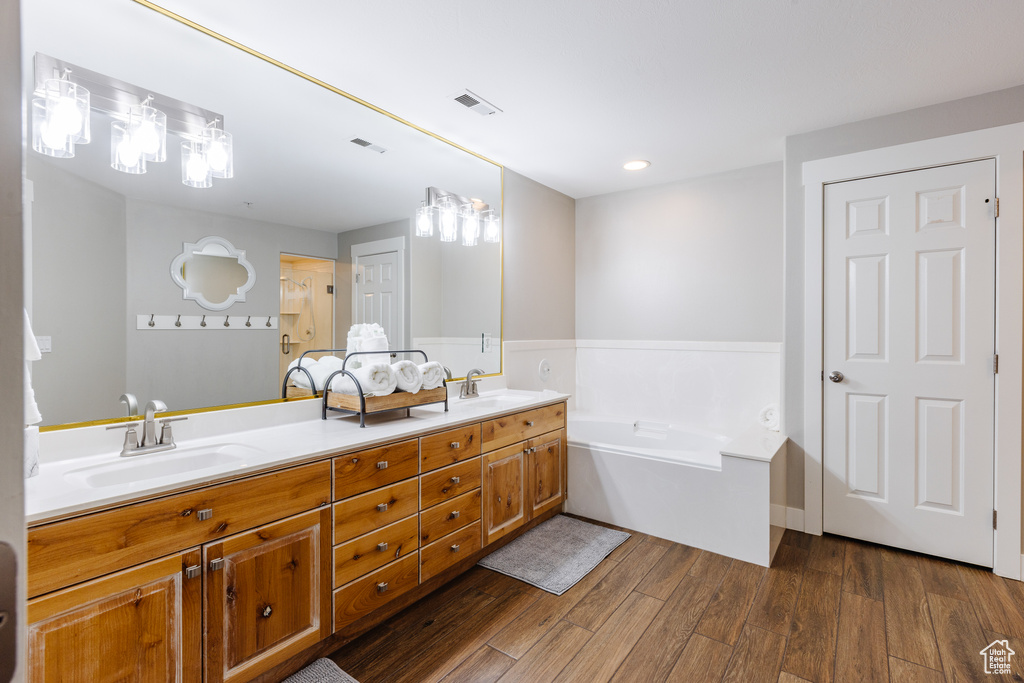 Bathroom with visible vents, a sink, wood finished floors, and double vanity